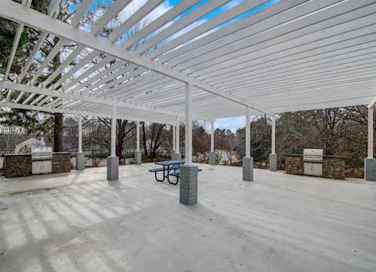 a covered patio with a table and a bench under a white roof  at The Sapphire, Decatur, GA