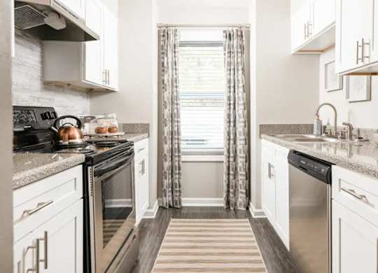 a kitchen with stainless steel appliances and white cabinets at The Sapphire, Decatur, Georgia