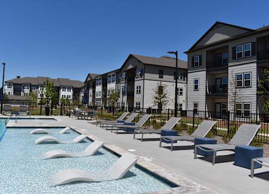 a swimming pool with lounge chairs in front of apartment buildings at Century Mundy Mill Apartments, Oakwood