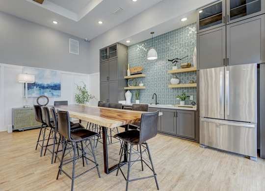 a kitchen with stainless steel appliances and a wooden table with chairs at Century Mundy Mill Apartments, Georgia