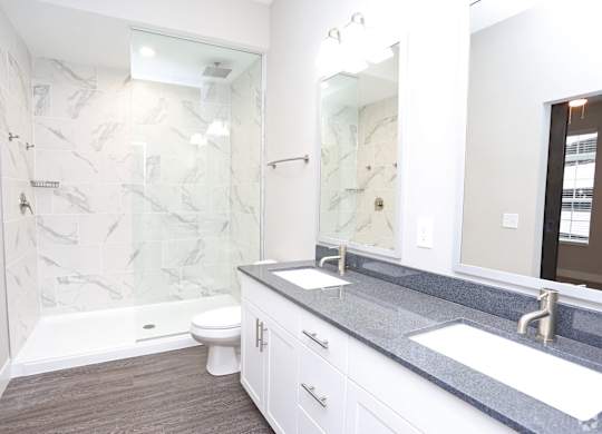 a bathroom with a shower and a sink and a mirror at Century Baxter Avenue, Louisville, KY 40204