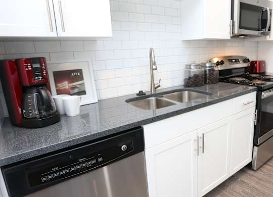 a kitchen with white cabinets and a counter with a sink at Century Baxter Avenue, Louisville Kentucky