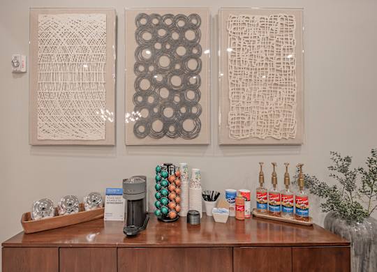 three pieces of artwork hanging on the wall above a counter with coffee and other items at Century HomePlace, Prattville, 36066