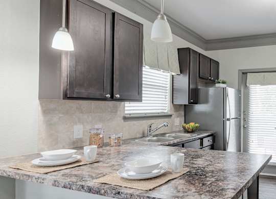 a kitchen with a marble counter top and a stainless steel refrigerator at Century HomePlace, Prattville, AL