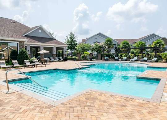 a large swimming pool with chairs around it in front of a house at Century HomePlace, Alabama