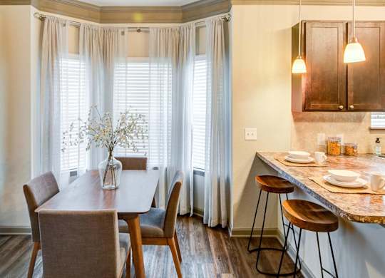 a dining room with a table and chairs and a kitchen with windows at Century HomePlace, Alabama