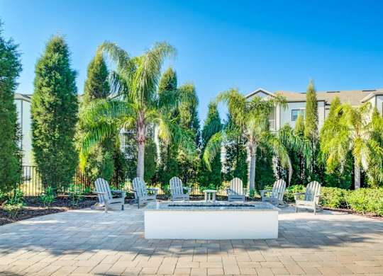 A patio with a white table surrounded by trees and chairs.at Century Ariva, Florida