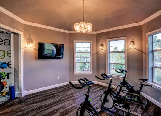 A room with a television, a window, and exercise bikes.at Century Ariva, Lakeland, FL 33812