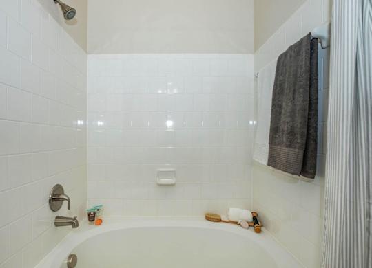 A white tiled bathroom with a white bathtub and a shower head.at Century Cedar Hill, Texas, 75104