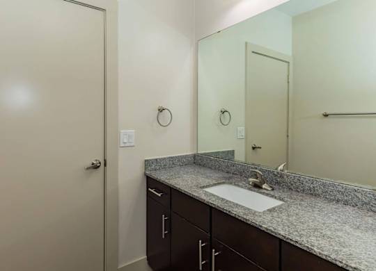 A bathroom with a sink, mirror, and cabinets.at Century Cedar Hill, Cedar Hill, TX
