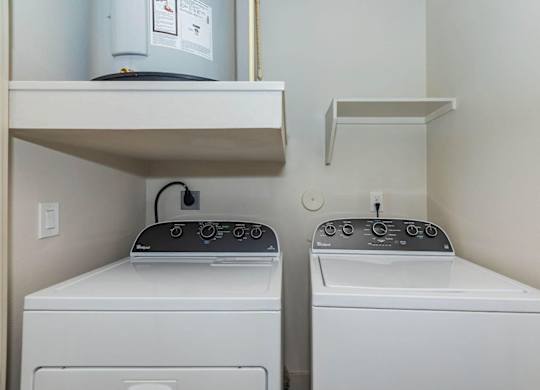 Two washing machines in a small laundry room.at Century Cedar Hill, Cedar Hill Texas