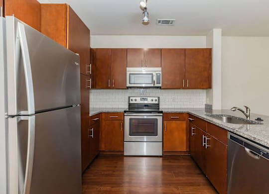 A kitchen with a refrigerator, oven, and microwave.at Century Cedar Hill, Cedar Hill