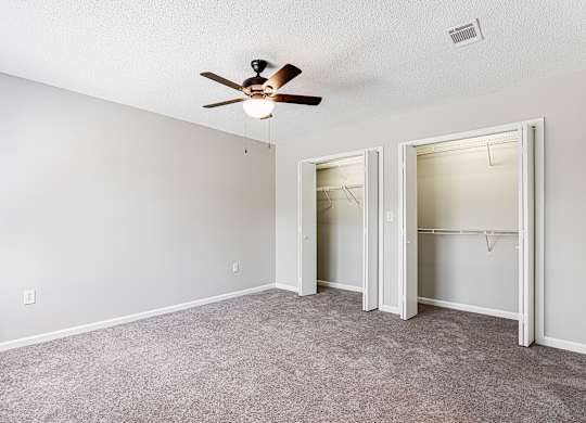 Empty bedroom with dual closets and ceiling fan at Salem Glen Apartments, Conyers, GA