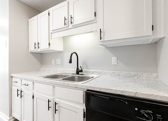 Compact kitchen with white cabinetry and marble countertops at Salem Glen Apartments, Georgia