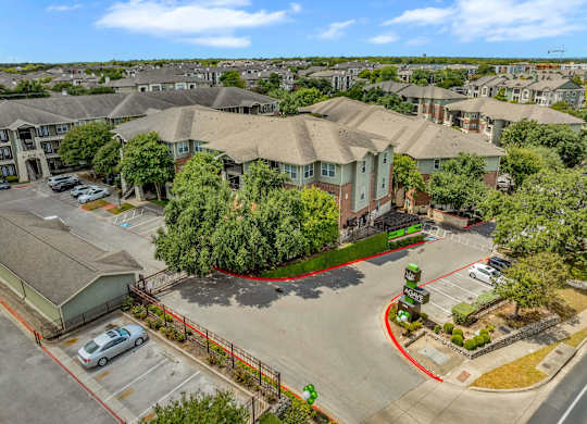 A large apartment complex with a parking lot in front.