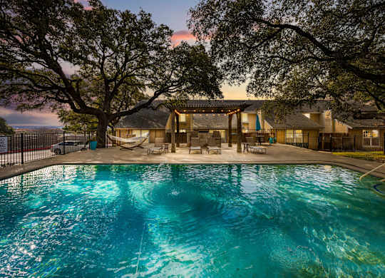 A large swimming pool in front of a house surrounded by trees.