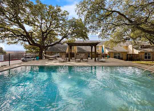 A swimming pool surrounded by trees and a gazebo.