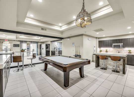 A room with a pool table and bar area.