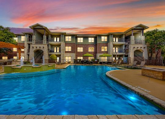 A large swimming pool in front of a multi-story residential building.