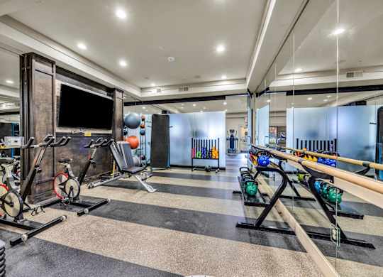 A gym with a variety of equipment including treadmills, weights, and exercise machines.