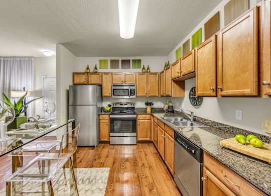 A kitchen with wooden cabinets and a glass table.
