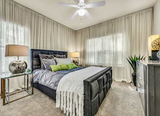 A bedroom with a large bed and a ceiling fan.