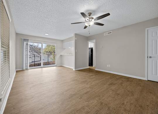 A spacious room with a ceiling fan and wooden flooring.