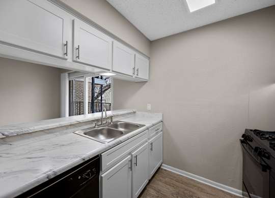 A kitchen with white cabinets and a marble countertop.