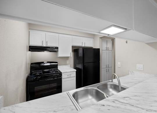 A kitchen with a black refrigerator, white oven, and a stainless steel sink.