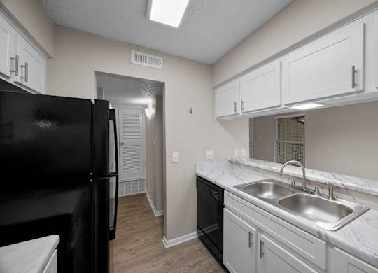 A kitchen with black appliances and white cabinets.