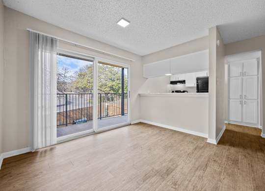 A spacious room with a sliding glass door leading to a balcony.