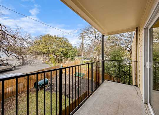 A balcony with a black railing and a green trash can.
