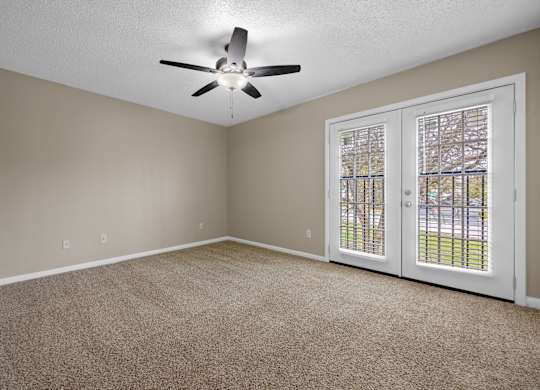 A room with a ceiling fan and carpeted floor.
