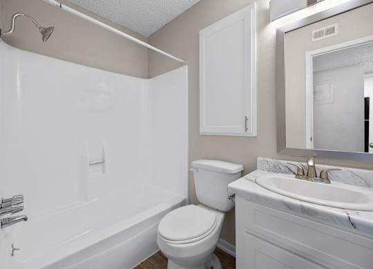 A white bathroom with a toilet, sink, and bathtub.