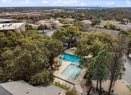 A swimming pool surrounded by trees in a residential area.