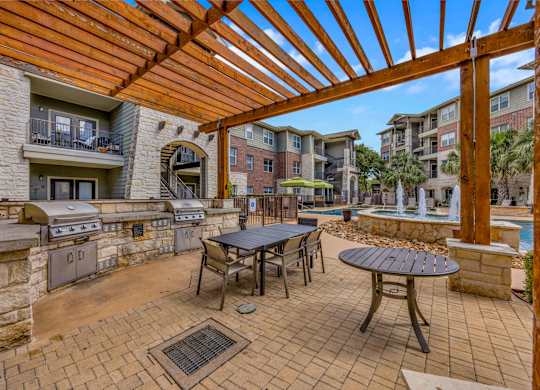 A patio with a table and chairs under a wooden pergola.