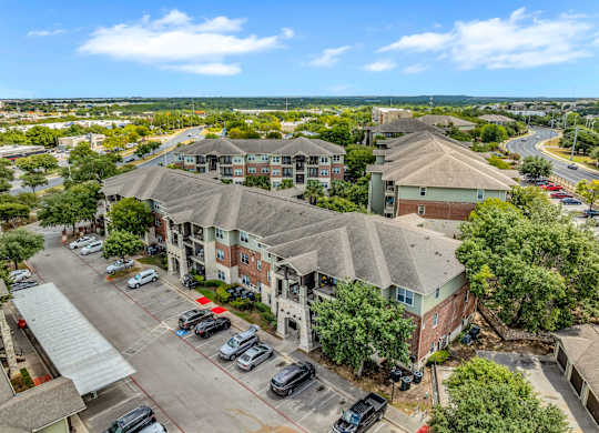 A large apartment complex with a parking lot in front.