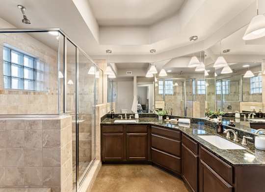 A large, well-lit bathroom with a walk-in shower and double sinks. at Bridge at Heritage Woods, Austin, TX