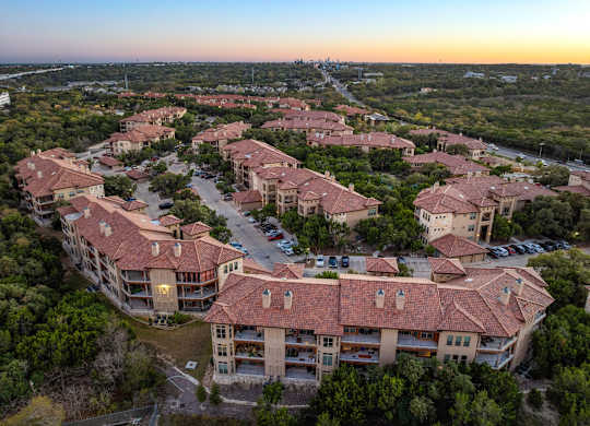 A sunset view of a large residential complex with multiple buildings and parking lots. at Bridge at Heritage Woods, Austin, Texas