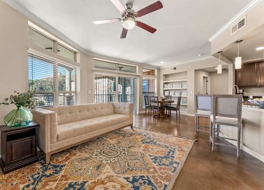 A living room with a beige couch, a rug, and a ceiling fan. at Bridge at Heritage Woods, Austin, 78753
