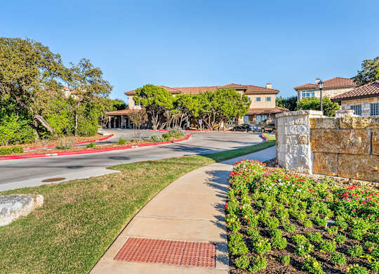 A residential street with houses on both sides and a sidewalk in the foreground. at Bridge at Heritage Woods, Texas, 78753