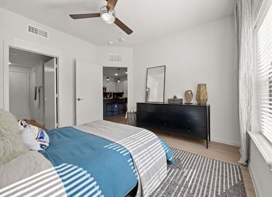 A bedroom with a bed, a dresser, and a mirror. at Bridge at Tech Crossing, Austin, Texas