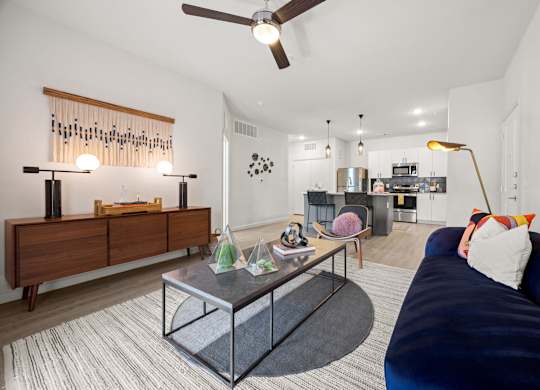A modern living room with a dark blue couch and a glass coffee table. at Bridge at Tech Crossing, Austin, TX