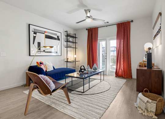 A living room with a blue sofa and a wooden chair. at Bridge at Tech Crossing, Austin, Texas