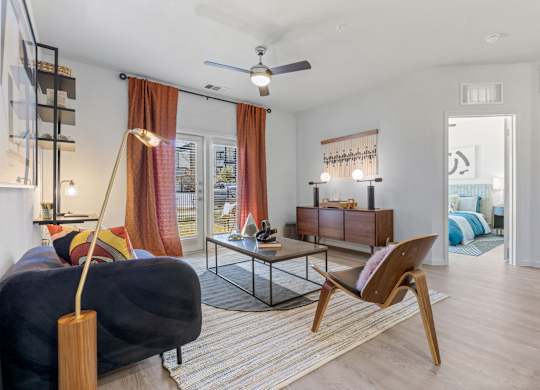 A living room with a black couch, a wooden chair, and a glass table. at Bridge at Tech Crossing, Austin