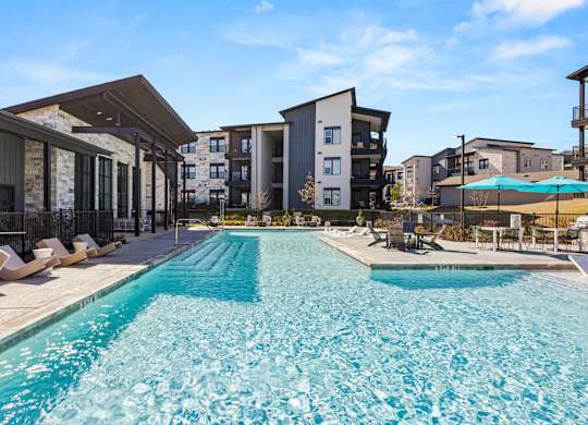 A large swimming pool in front of apartment buildings. at Bridge at Tech Crossing, Austin, TX, 78753