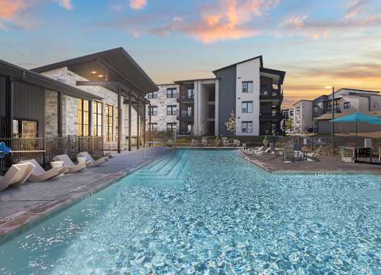 A swimming pool in front of apartment buildings at sunset. at Bridge at Tech Crossing, Austin, Texas
