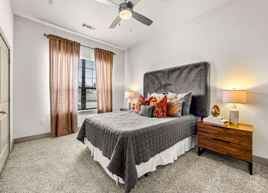 A bedroom with a large bed, a ceiling fan, and a window with curtains. at The Royce at 8100, Austin, 78729