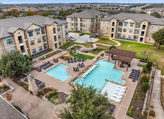 A large swimming pool surrounded by a grassy area and apartment buildings. at The Royce at 8100, Austin, TX, 78729