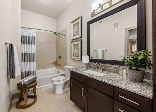 A bathroom with a white toilet, a sink, and a shower. at The Royce at 8100, Texas